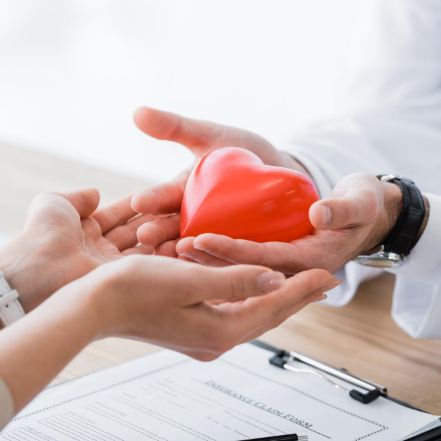 A pair of hands transferring a heart-shaped model to another, signifying personal health. A pair of hands transferring a heart-shaped model to another, signifying personal health.
